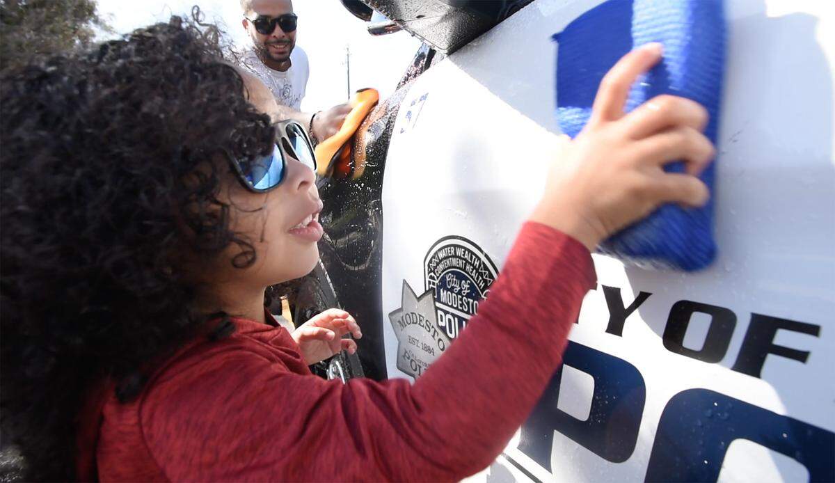 Julian Williams, 3 and his father Devonte wash a Modesto Police patrol car as volunteers worked on community projects throughout the city as part of Love Modesto in Modesto, Calif., on Saturday, April 30, 2022.