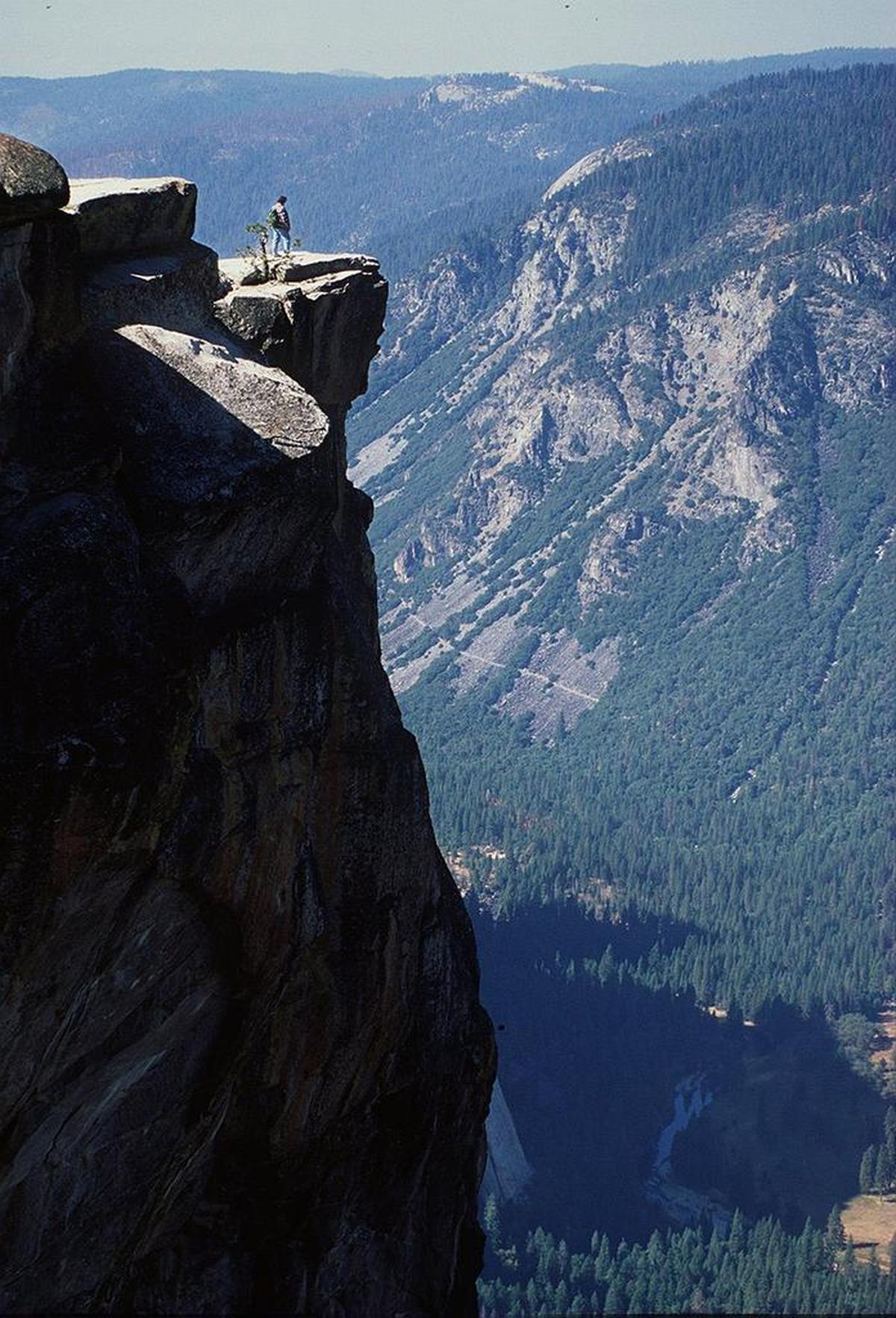 A hiker, overlooking Yosemite Valley and the Merced River, takes in the view near Taft Point in Yosemite National Park. This 7,500-foot-high promontory is where Dean Potter and Graham Hunt died in 2015 while attempting a BASE jump.