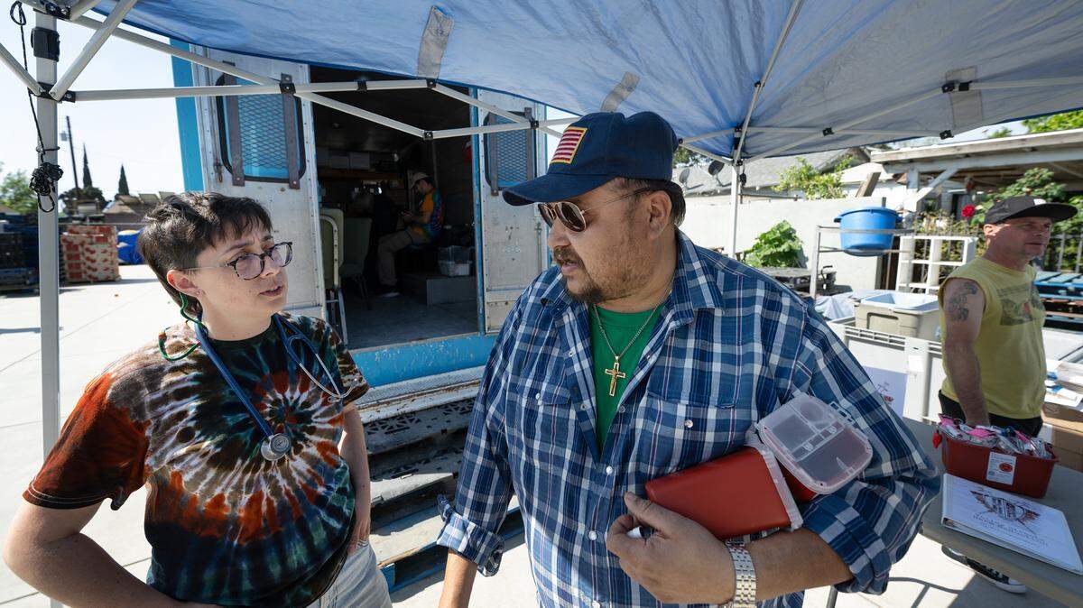 La doctora Andie Silva (izquierda), médico especialista en reducción de daños de Valley Streetz, habla con Juan Paz, de Merced, sobre su estado de salud en The Rock Church, en el distrito del Aeropuerto, en Modesto, California, el viernes 12 de abril de 2024. El programa ofrece servicios de reducción de daños y tratamiento médico en la iglesia los viernes por la mañana.