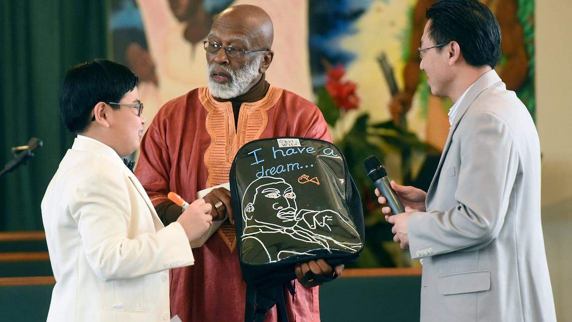Hien Ho (left) shows off his invention of a writable backpack Monday (01-16-17) during the 30th Martin Luther King Jr. Day Service at Christian Love Baptist Church in Modesto, Calif. Also pictured are Rev. James Anderson (center) and Ho’s father Anviet Nguyen.