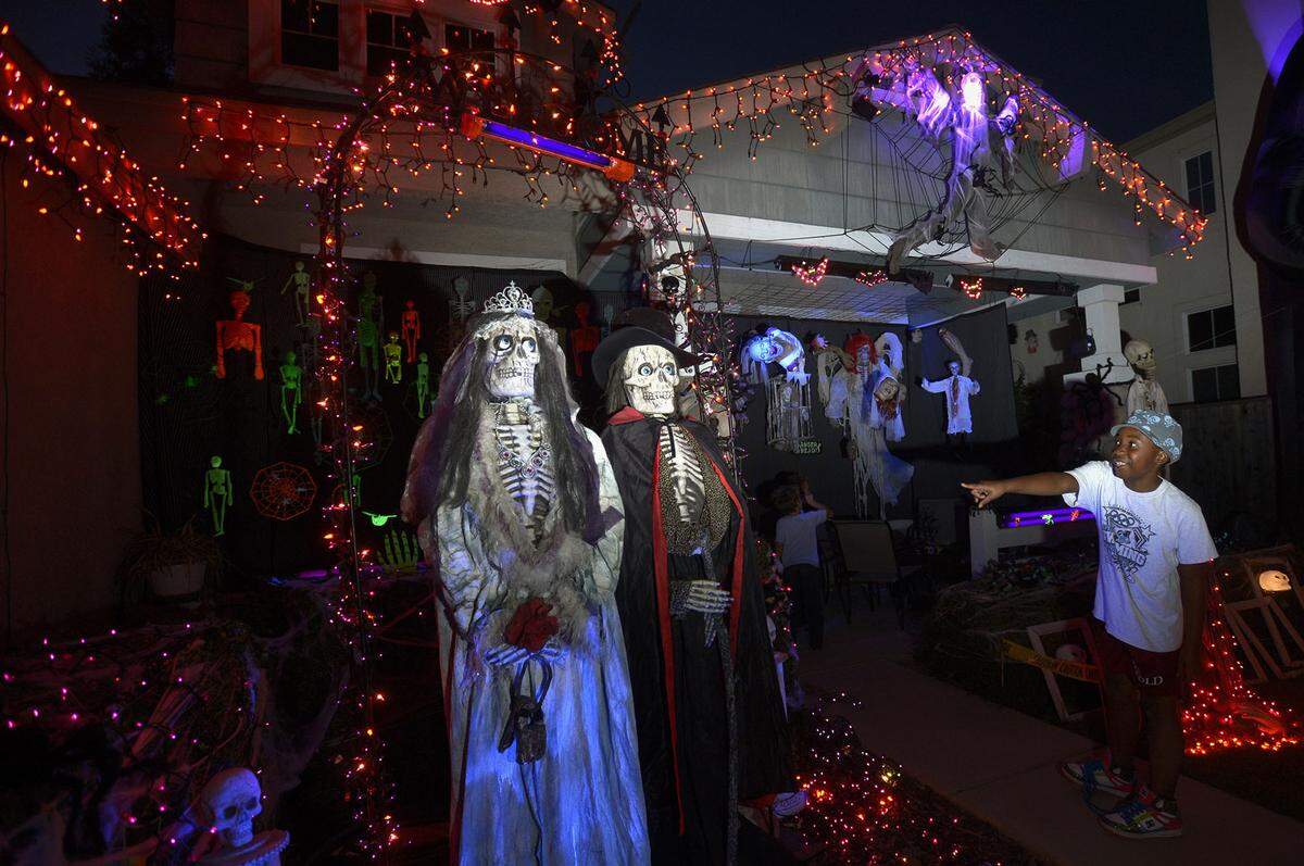 Neighbor, Addie Mettler, age 8, points to the bride and groom skeletons at the Halloween display at the home of Stephanie Valgos in Turlock on Merchant Ln. (10-22-13) at night.