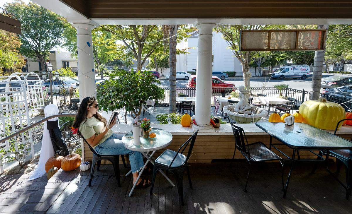Leah Bryand reads a book on the porch at Queen Bean Coffee & Social House in Modesto, Tuesday, Oct. 22, 2024.