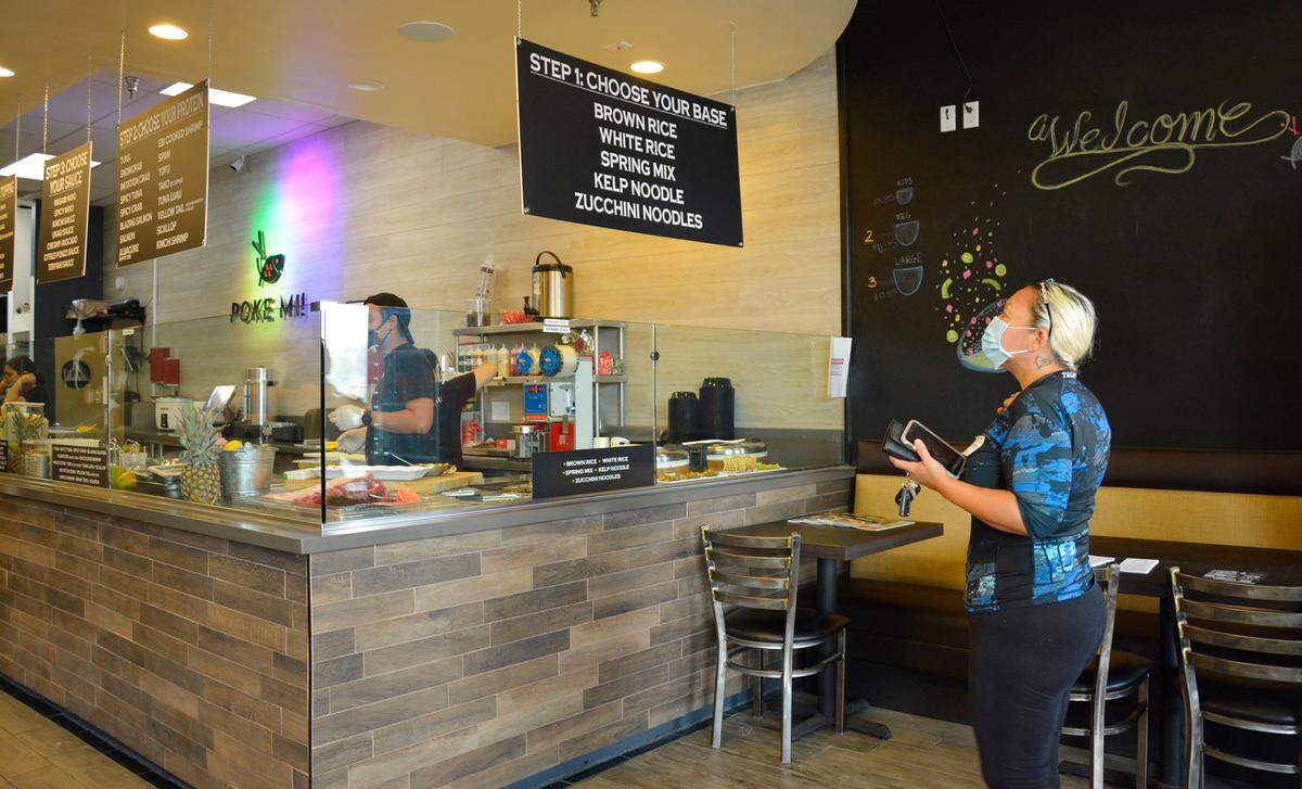 Merced resident Desiree Cady looks at the menu at the new McHenry Village restaurant Poke Mi! in Modesto, Calif.