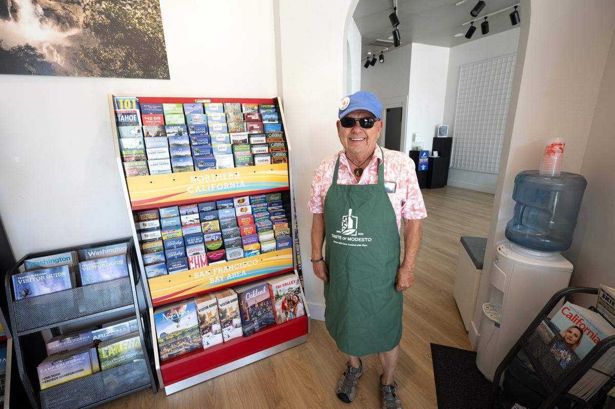 Visit Modesto’s welcome center is selling Modesto themed “swag” like the apron modeled by service agent Bob Searls in Modesto, Friday, July 18, 2025. The Stanislaus Arts Council Gallery and Visit Modesto now share space at the gallery’s J Street location.