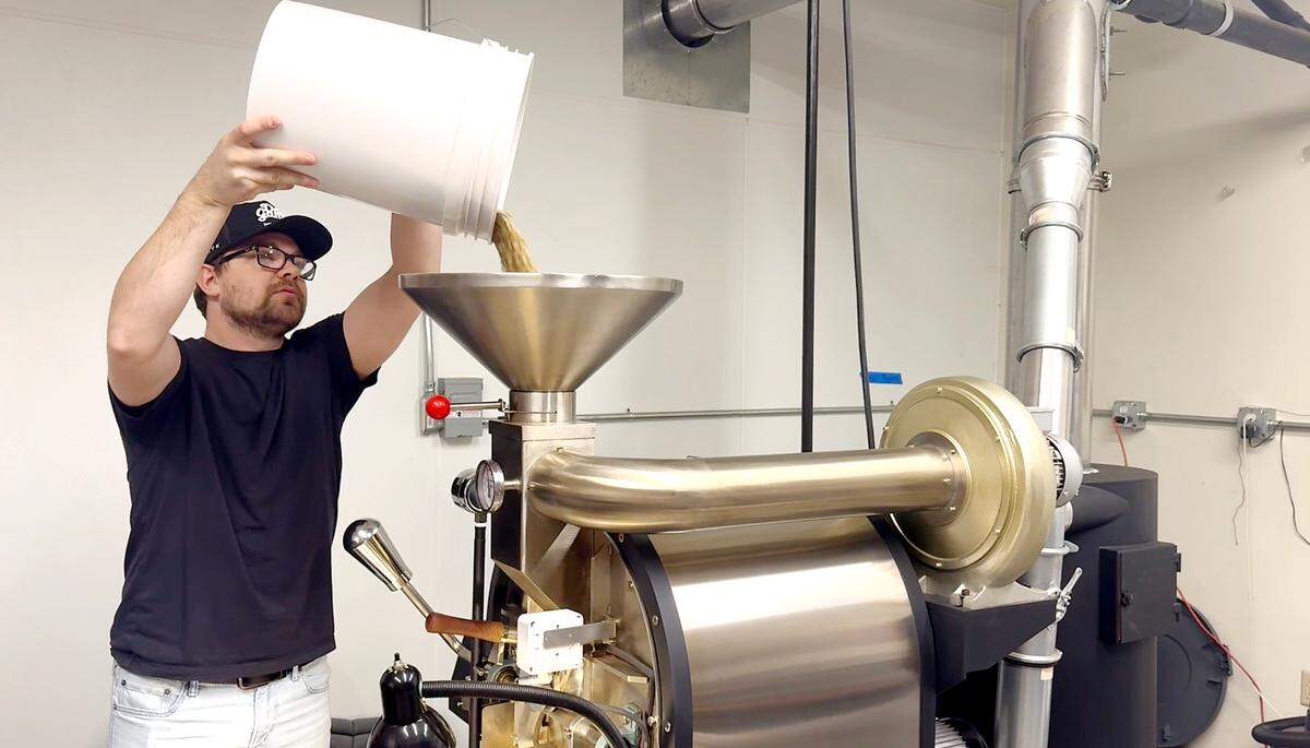 Manager Isaiah Villines pours coffee beans into roasting machine at Volente Coffee Roasters in Modesto, Friday, Jan. 10, 2025.