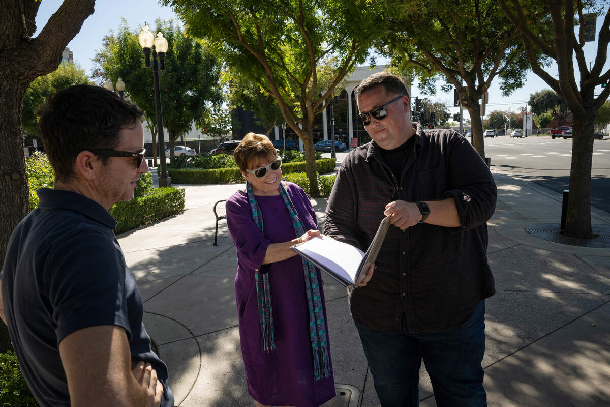Authors David Seymour, right, and Keith Highiet look at the second edition of “StaniStory: Change and Continuity in Stanislaus County” with Ann Veneman outside the Gallo Center of the Arts in Modesto, Monday, Oct. 20, 2025. Veneman, former U.S. Secretary of Agriculture, appears in the section on extraordinary women.