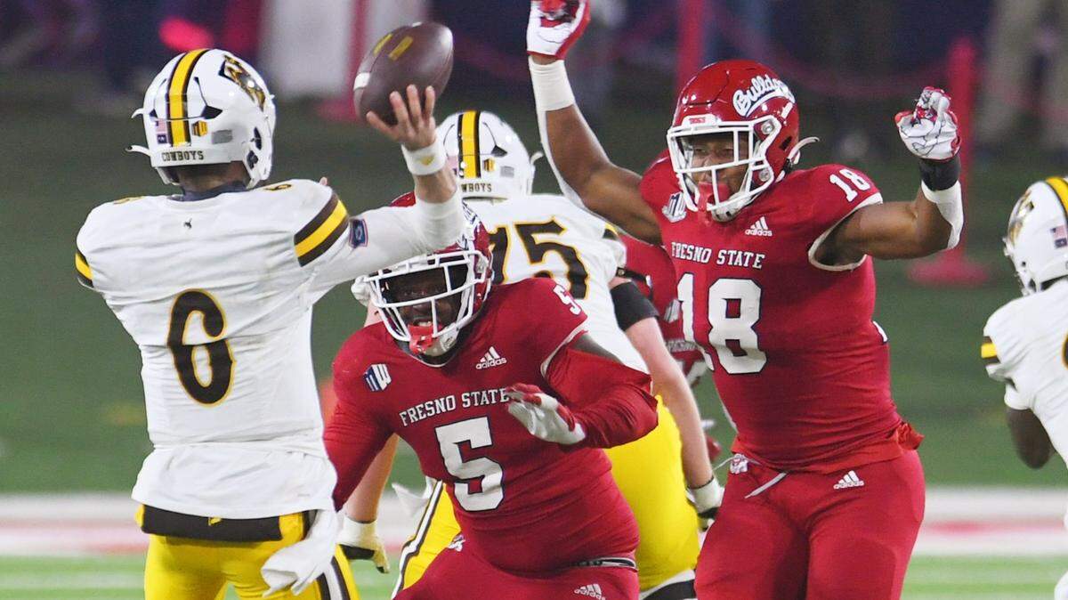 Fresno State’s Demo Bridges, center, and Isaiah Johnson, right, pressure Wyoming quarterback Andrew Peasley, left, in game action Friday, Nov. 25, 2022 in Fresno. The Bulldogs led 23-0 at halftime.