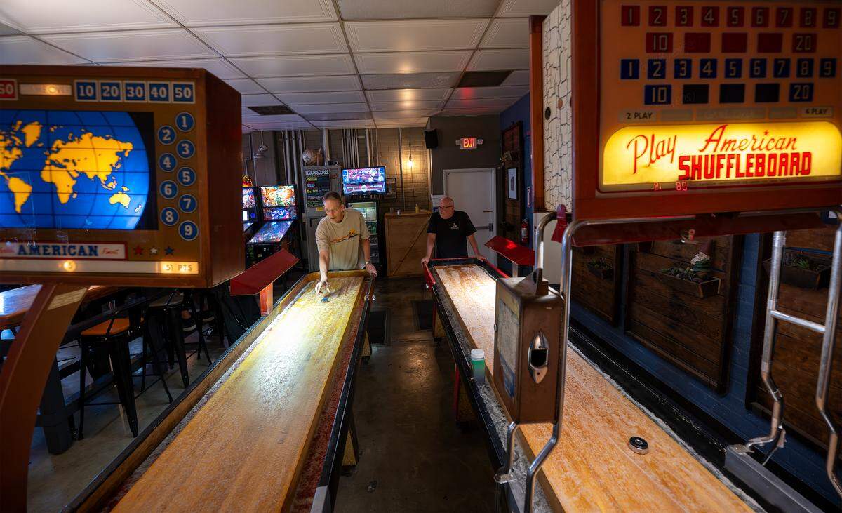 Jim Myers, left, plays shuffleboard at Contentment Brewery in Modesto on Oct. 22, 2025.