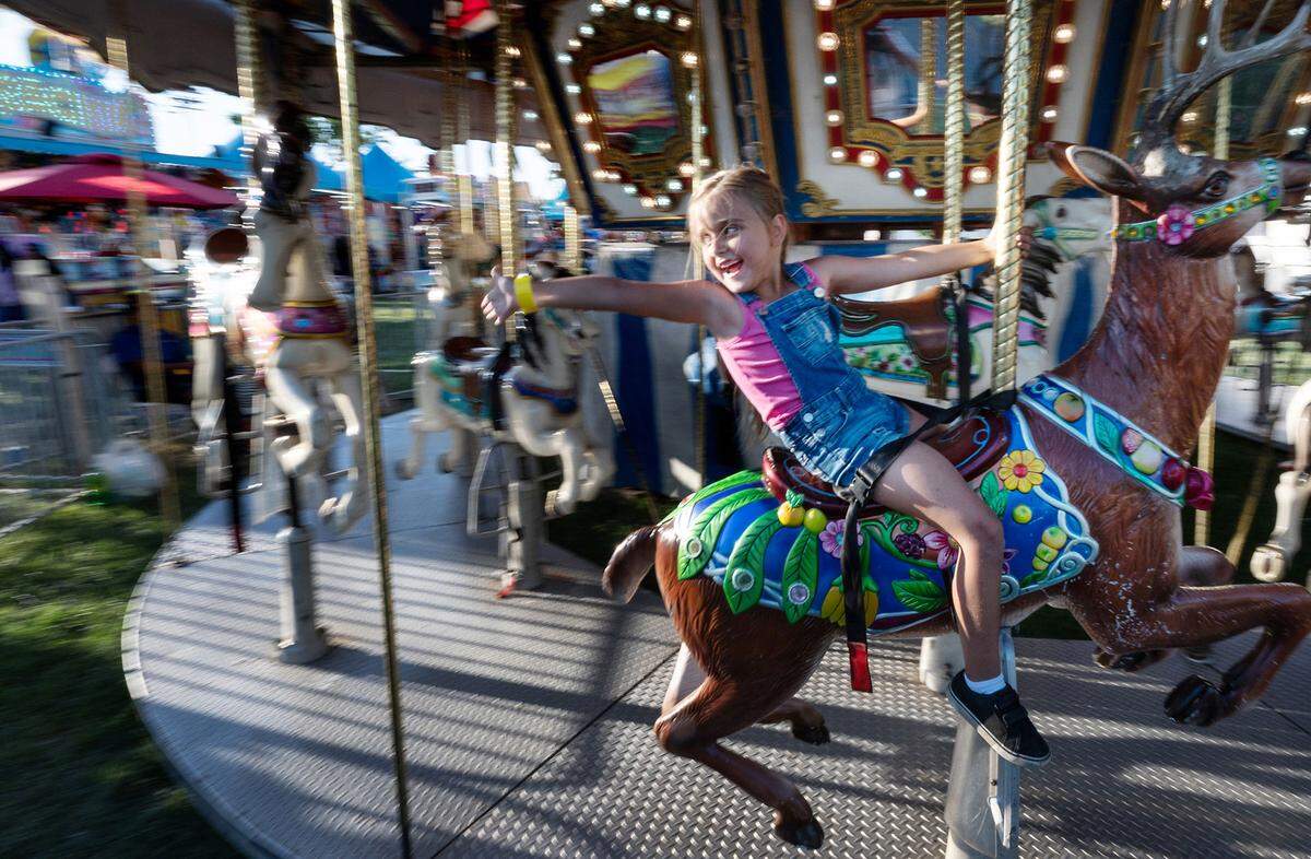 Julianna Kentra, 6, waves to her parents as she rides the carousel at the Stanislaus County Fair in Turlock, Calif., Friday, July 7, 2023.