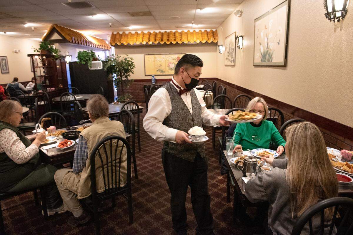 Server Jimmy Qin delivers food to some lunch guests at Beijing Restaurant in Modesto, Calif., Thursday, Dec. 15, 2022.