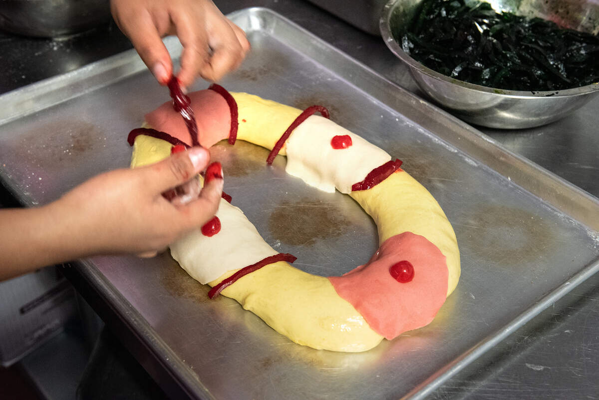 Berenice Reyes decora el pan dulce navideño con acitrones confitados en Canseco's Bakery en Modesto, California, el miércoles 5 de enero de 2022. El personal ha estado ocupado atendiendo pedidos para el Día de los Reyes Magos.