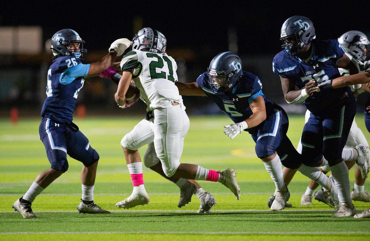 Downey defenders Richard Williams (5) and Pablo Garcia (26) trap Pitman’s Jose Zamora behind the line of scrimmage during the Central California Athletic League game at Downey High School in Modesto, Calif., Friday, Oct. 28, 2022.