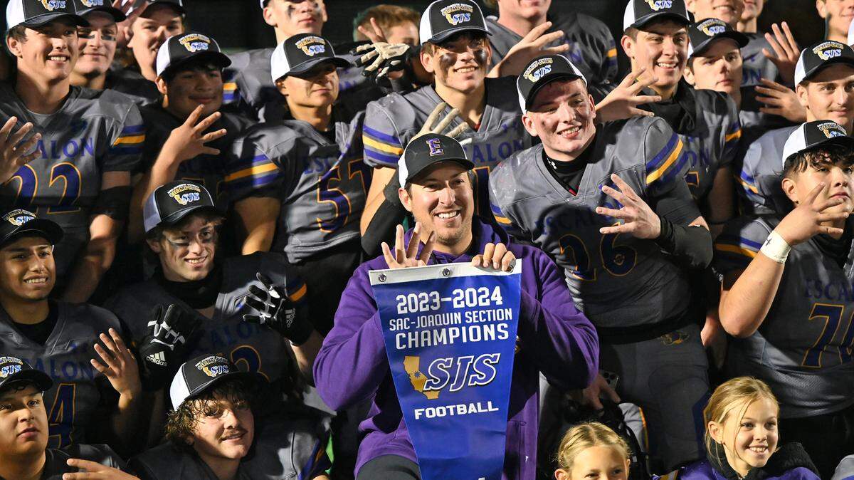 Head Coach Andrew Beam and his players pose for pictures with the section banner at St. Mary’s High School in Stockton, Calif., Friday, Nov. 24, 2023. 