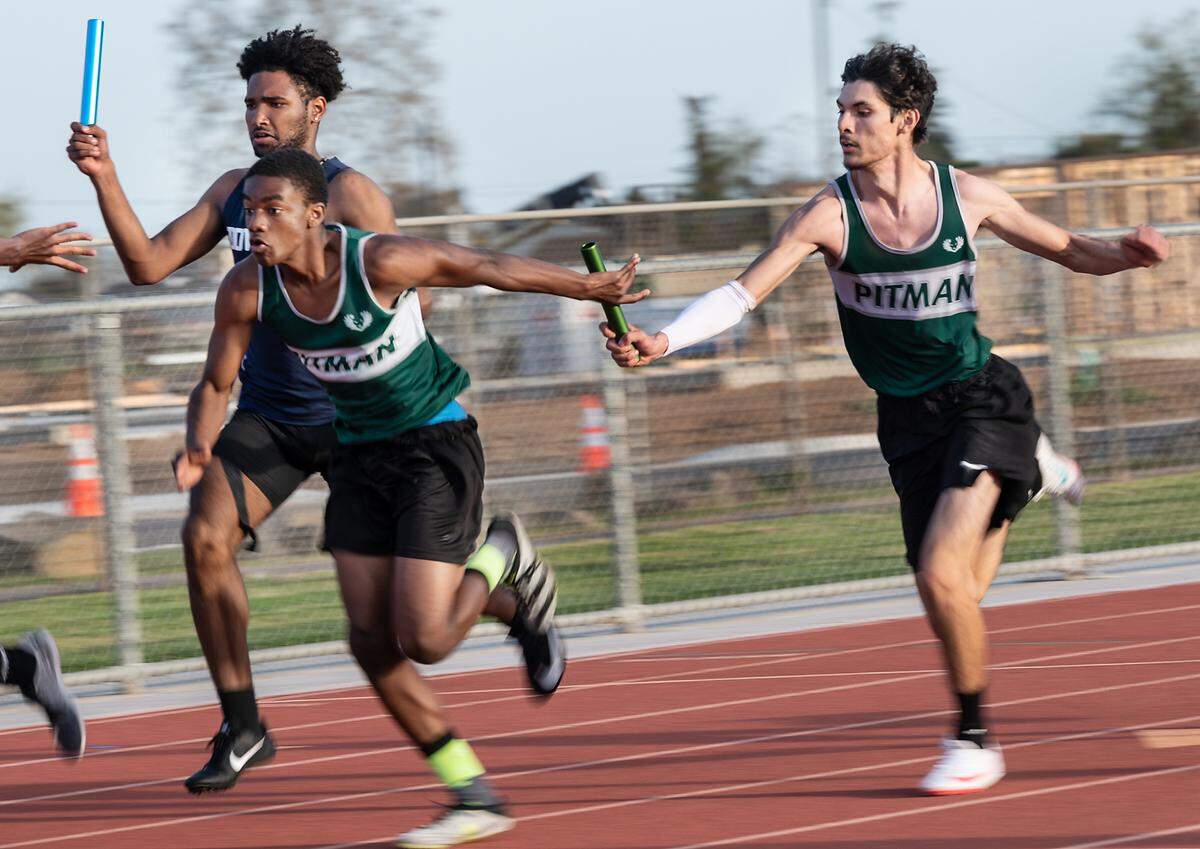 Pitman boys 4X100 relay runners Cruzito Garcia, right, and Sean Fort exchange the baton during the Stanislaus County Championships on Friday, March 18, 2022, at Riverbank High School in Riverbank, Calif. Pitman finished second in the race.