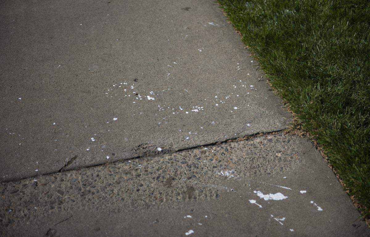 White paint is seen on a sidewalk near Doctors Medical Center in Modesto on Wednesday, April 8, 2026, after a protest the night before. Police said two people were arrested on suspicion of felony vandalism.