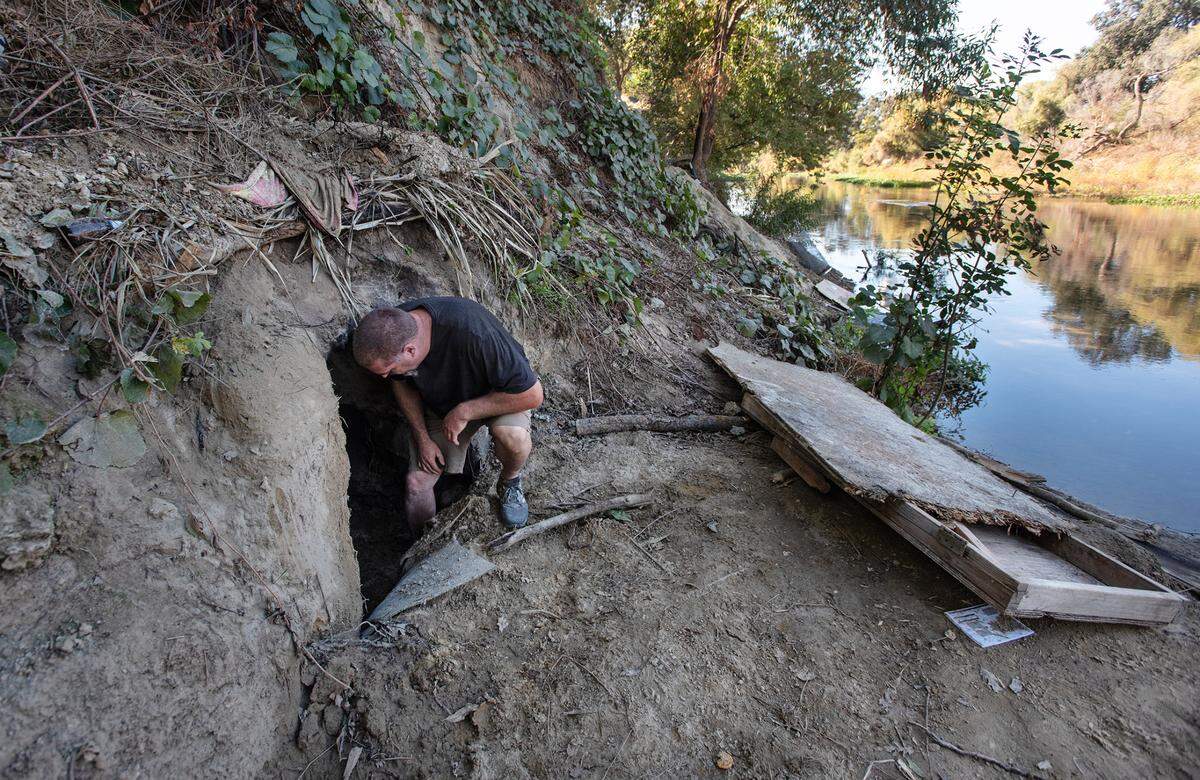Chris Guptill looks into a dugout cave along the south side of the Tuolumne River near Crater Avenue in west Modesto, Calif., Thursday, Oct. 27, 2022.