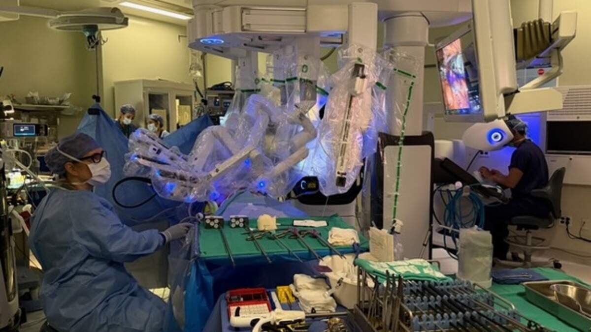In the operating room, transplant surgeon Dr. Janet Bellingham stays at Alyson Chavez’s side, working with transplant surgeon Dr. Eric Miller, who controls the da Vinci 5 robot to perform her kidney removal on June 9, 2026, at Sutter Health’s California Pacific Medical Center Van Ness Campus in San Francisco.