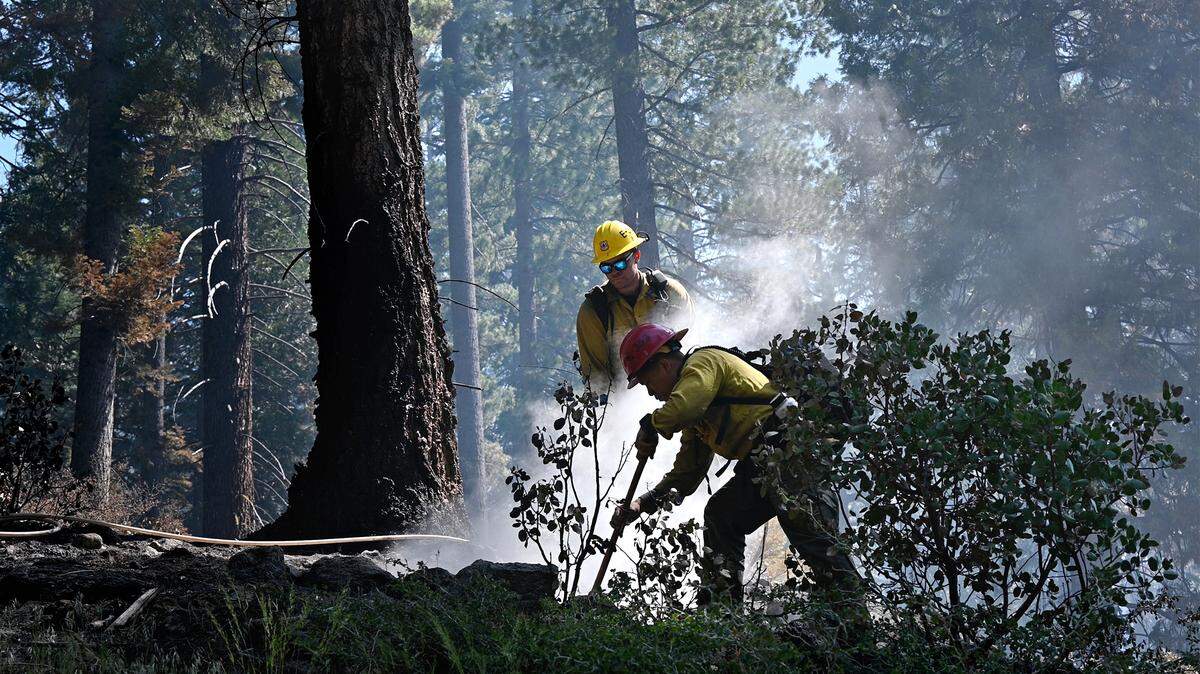 Eldorado National Forest firefighters Cai Phuong, front, and Alex Stanfield mop up hot spots after a prescribed burn in the Stanislaus National Forest in California, on May 20, 2022.