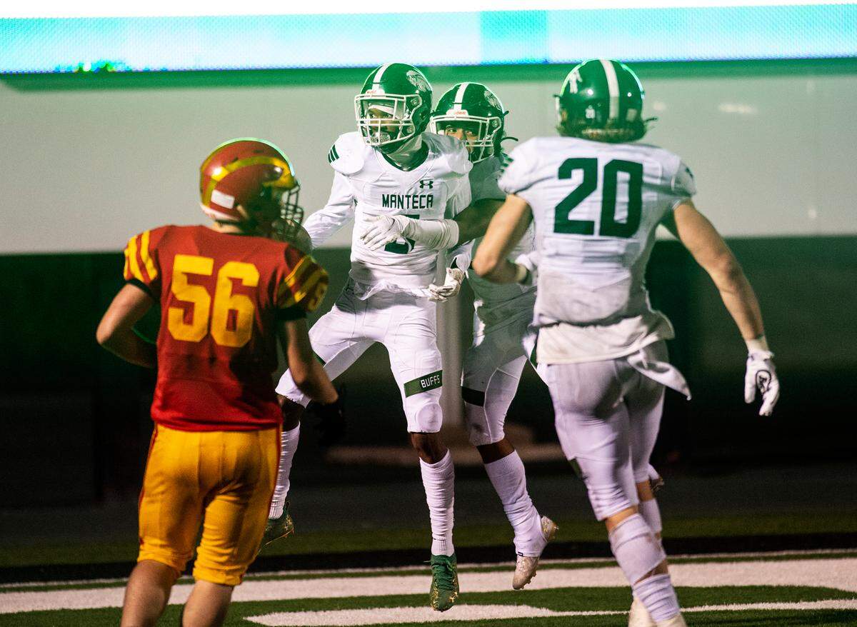 Manteca’s Zion Allen and teamamates celebrate the winning fourth quarter touchdown during the Sac-Joaquin Section Division III championship game with Oakdale at St. Mary’s High School in Stockton, Calif., on Friday, Nov. 25, 2021.
