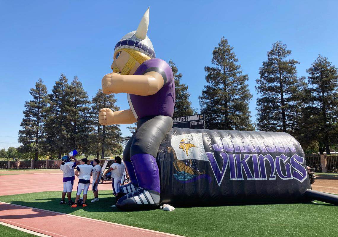 Members of the varsity football team take a break from the heat in the shade of the mascot tunnel at Johansen High School in Modesto, Calif., on Thursday, September 1, 2022. Thursday marked the first day the team could use its new artificial turf field for practice.