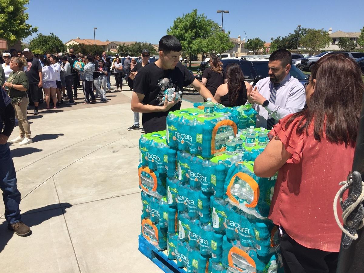 Bottled water is handed out as parents wait to pick up their children at Cesar Chavez Junior High after lockdown Monday.
