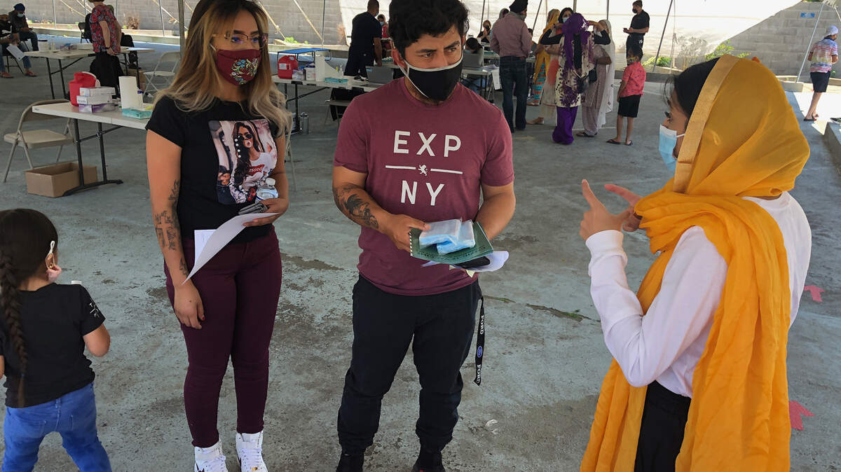 Navroop Kaur, a community organizer for the Jakara Movement, gives educational materials to people who got the COVID-19 vaccine at the Turlock Gurdwara on May 23, 2021. Some Sikh Americans in Turlock, Calif. said the vaccine is much more difficult to access for friends and family in India.