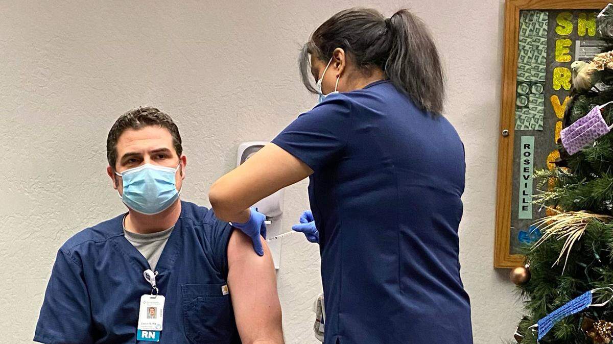 Daren Sonnenberg, ICU nurse, receives the first dose of the COVID-19 vaccine at Memorial Medical Center in Modesto on Friday, Dec. 18, 2020. Kelly Dhesi, manager of critical care, is administering the shot.