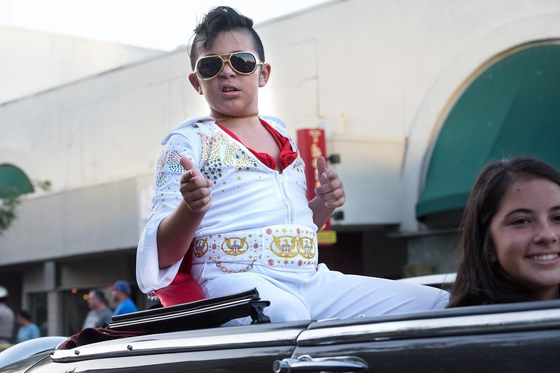 Mateo Elisary, 11, rides in the back of a classic car dressed as Elvis on 10th Street during the Graffiti Classic Car Parade in Modesto, Calif., Friday, June 8, 2018.