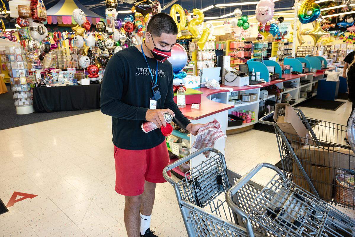 Sales associate Benito Marines cleans shopping carts at Party Guys in Modesto, Calif., on Thursday, June 10, 2021.