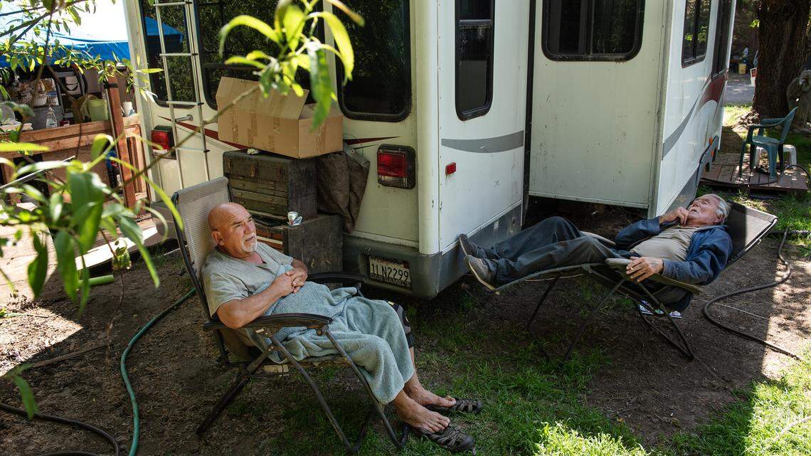 Miguel M. Vasquez, left, and David Safrans, right, relax outside at River’s Edge RV Park and Campgrounds in Knights Ferry, Calif., on Friday, April 16, 2021. Residents, many who are retirees and disabled people, pay monthly rent on fixed incomes. They recently received notices from the owner ordering them to leave in 30 days. The private campground, also including “tiny houses”, will be converted for short-term use.