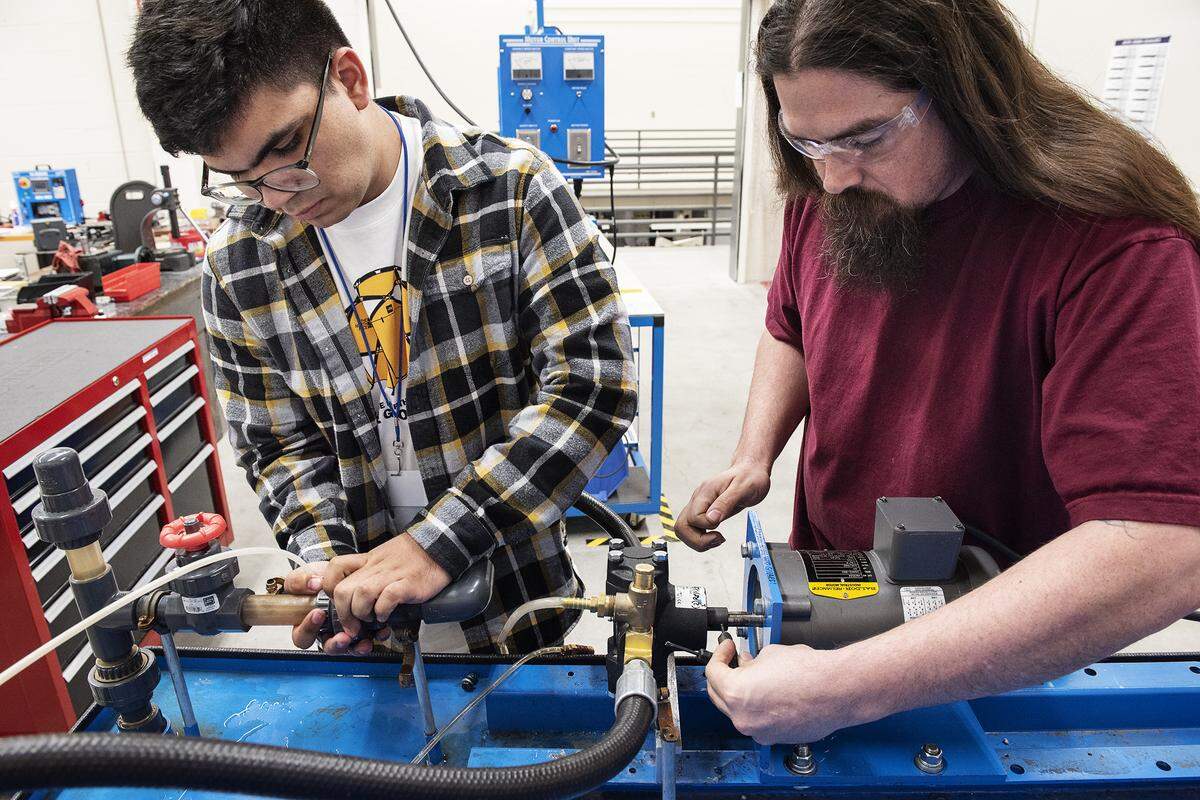Damian Suarez, left, and Dino Brochini install a pump at the VOLT Institute in Modesto, Calif., on Thursday, March. 5, 2020. Both men are students in the industrial maintenance mechanic program.