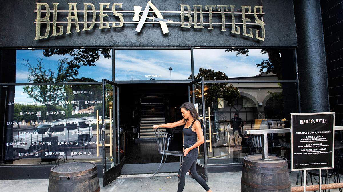 Hair stylist Precious Shephard helps clean and prepare for reopening at Blades & Bottles in Modesto, Calif., on Thursday, June 11, 2020.