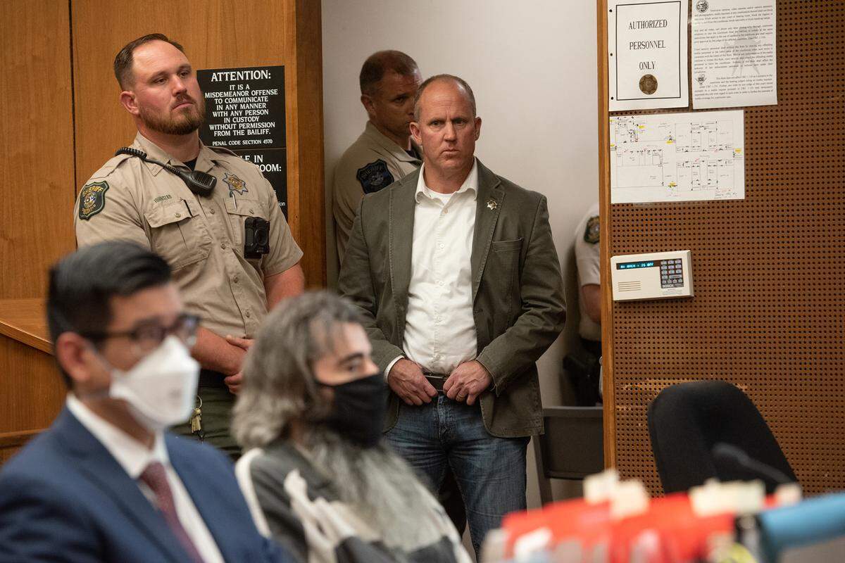 Stanislaus Sheriff Jeff Dirkse stands behind David Machado and watches as friends and family of Deputy Dennis Wallace give victim impact statements in Stanislaus Superior Court in May 2022.
