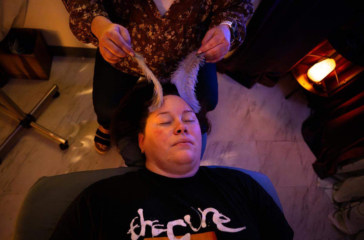 Scratched studio owner Sarah Kalinoff demonstrates ASMR-style soft touch therapy using feathers on Bee reporter Dominique Williams in Modesto, Thursday, May 21, 2026. 
