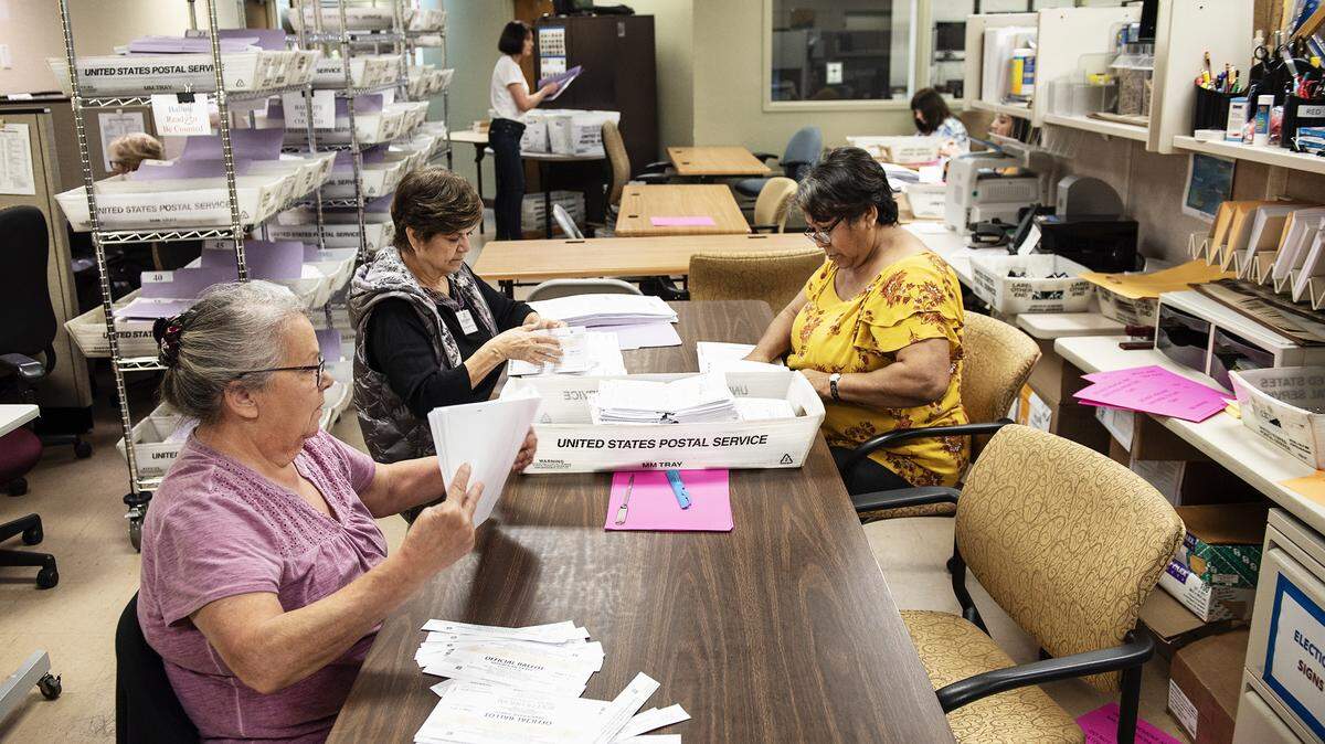 Geri Martin, left, Della Romandia, rear left, and Jeanette Mora flatten ballots before they are counted at the Stanislaus County Clerks Recorder’s office in Modesto, Calif., on Thursday, March. 5, 2020.
