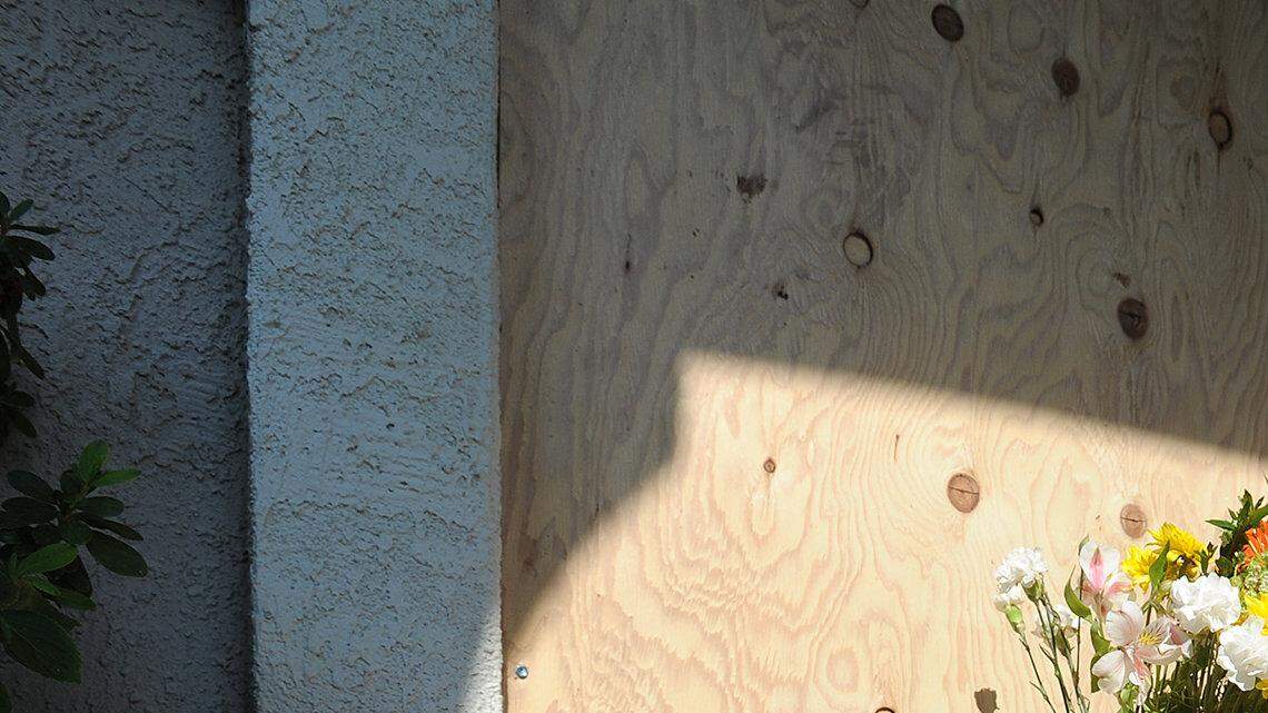 Flowers and candles sit in front of the boarded up door Friday afternoon (08-09-13) of the home belonging to Scott and Janet Pettit, who were discovered dead in the upstairs bedroom following a fire deemed suspicious.