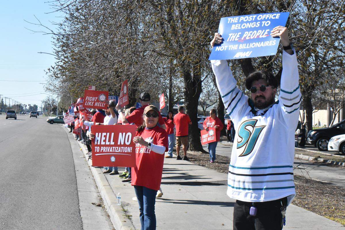 Postal worker Jorge Torres and retired postal worker Esther Fuson rally along Mitchell Road outside the Ceres post office on Sunday, March 23, 2025.
