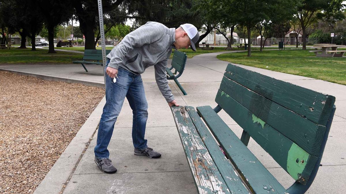 Jeff Pishney, the executive director of Love Modesto looks at benches in Mellis Park that are in need of paint and repair Wednesday morning April 18, 2018 in Modesto, Calif.