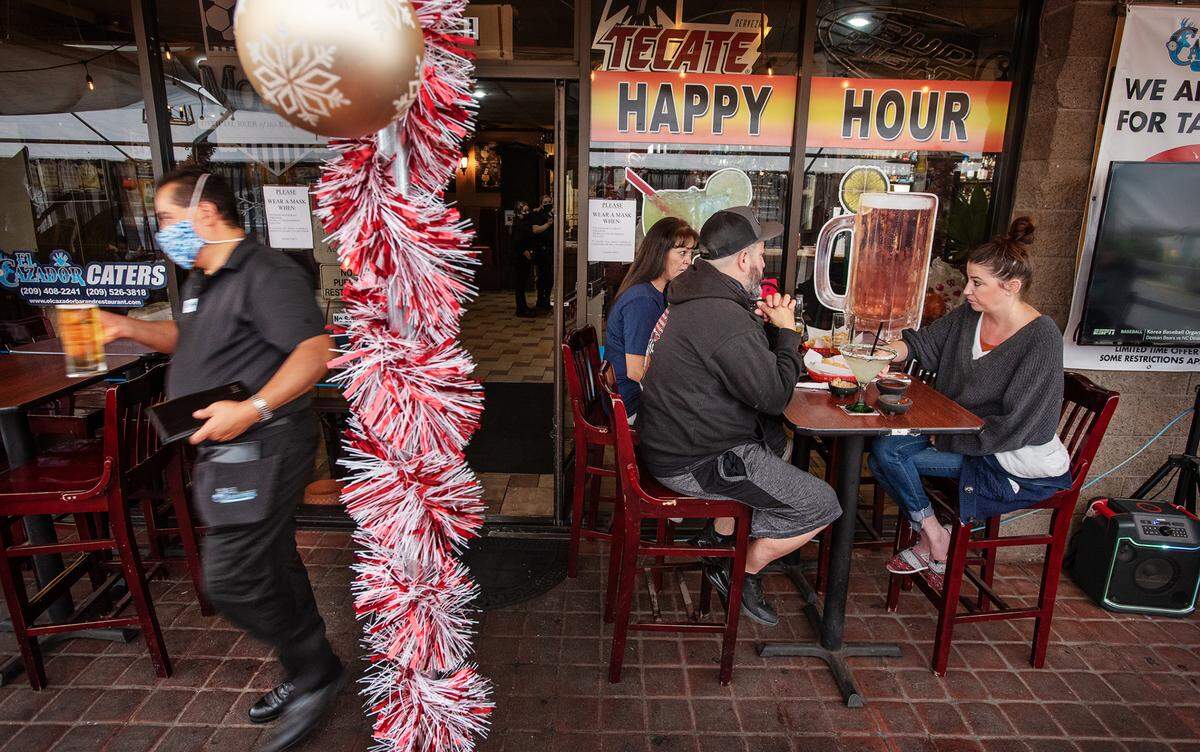 John and Natalie O’Neal, right, eat with a friend outside at El Cazador Mexican Restaurant in Modesto, Calif., on Tuesday, Nov. 17, 2020.