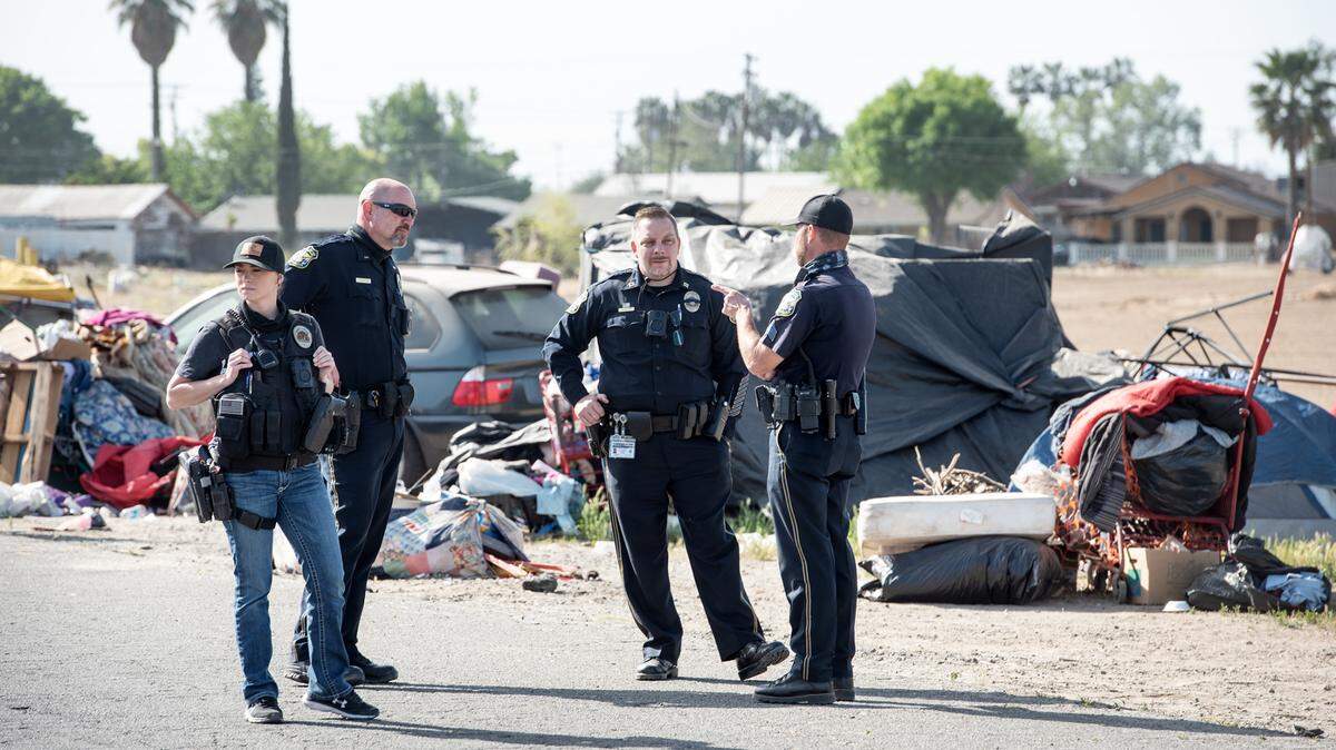 In this April 14, 2021 file image, Interim Turlock Police Chief Steven Williams, second from right, talks with officers during a homeless sweep on Glenwood Avenue in Turlock, Calif. Turlock’s 120-day homeless emergency ends in July.