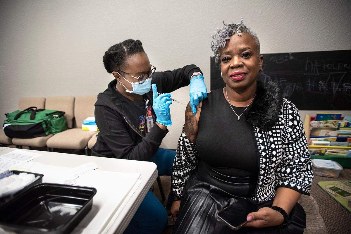 Gia Smith, right, gets a booster vaccine from RN Amina Edache at a vaccine clinic during the Modesto-Stanislaus NAACP Holiday Kwanzaa Social at Redeemer Modesto in Modesto, Calif., on Friday, Dec. 10, 2021.