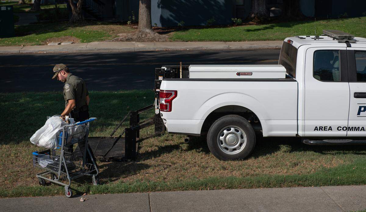 Modesto park ranger Justin Rocha picks up an abandoned shopping cart at Downey Park in Modesto, Calif., on Friday, September 9, 2022.