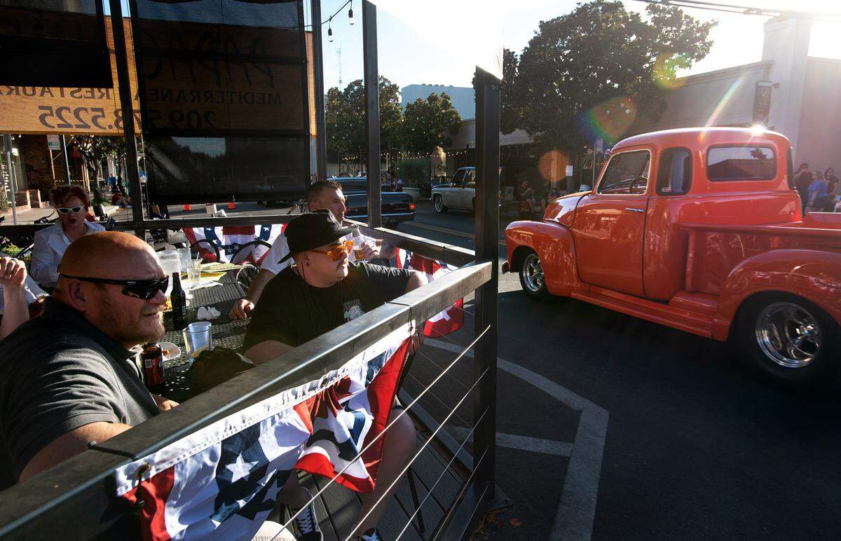 Richie Buchan, left, and his son Christian Buchan watch classic cars pass along J Street during the North Modesto Kiwanis Club’s “American Graffiti” car parade in Modesto, Calif., on Friday, June 10, 2022.