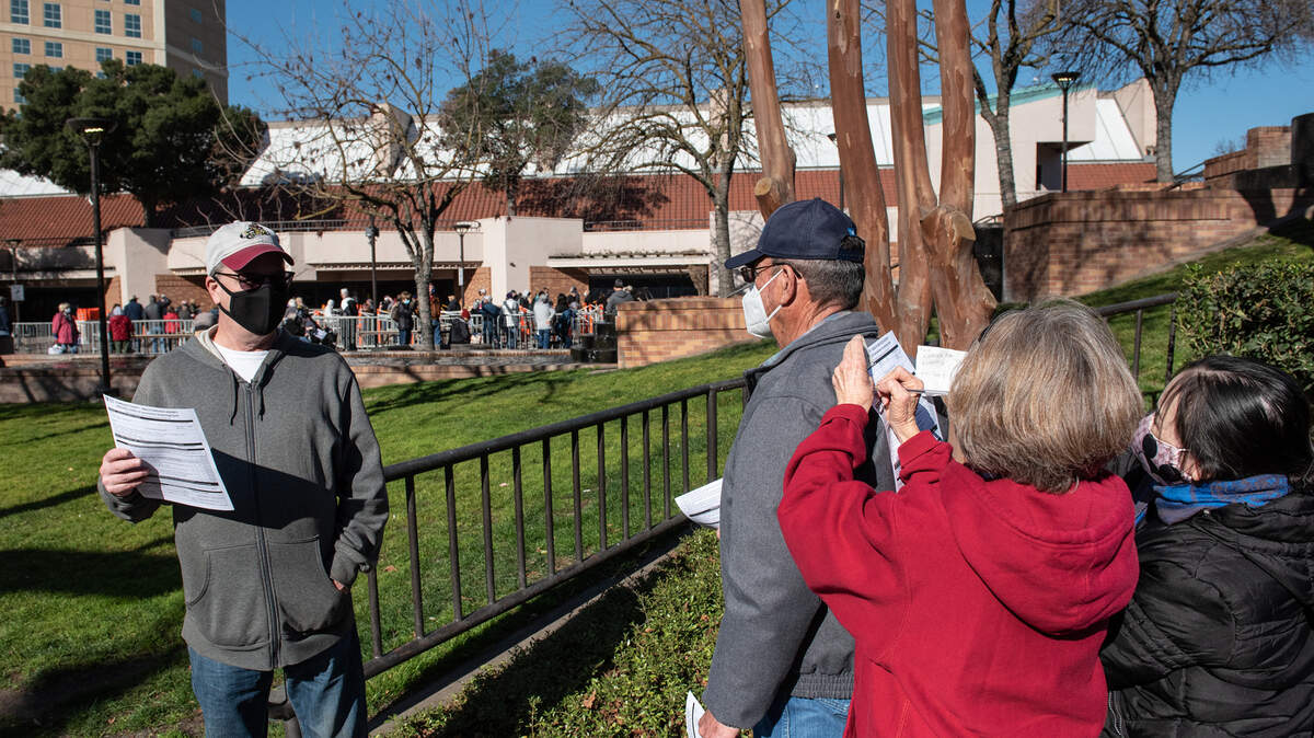 Mimi Medlen helps hong Tran fill out an authorization form as Stanislaus county residents wait to receive a COVID-19 vaccination at Modesto Centre Plaza in Modesto, Calif., on Thursday, Jan. 21, 2021. The clinics are for county residents or eligible people who work in Stanislaus County. Seniors 65 and older are asked to bring an ID or other proof of residence.