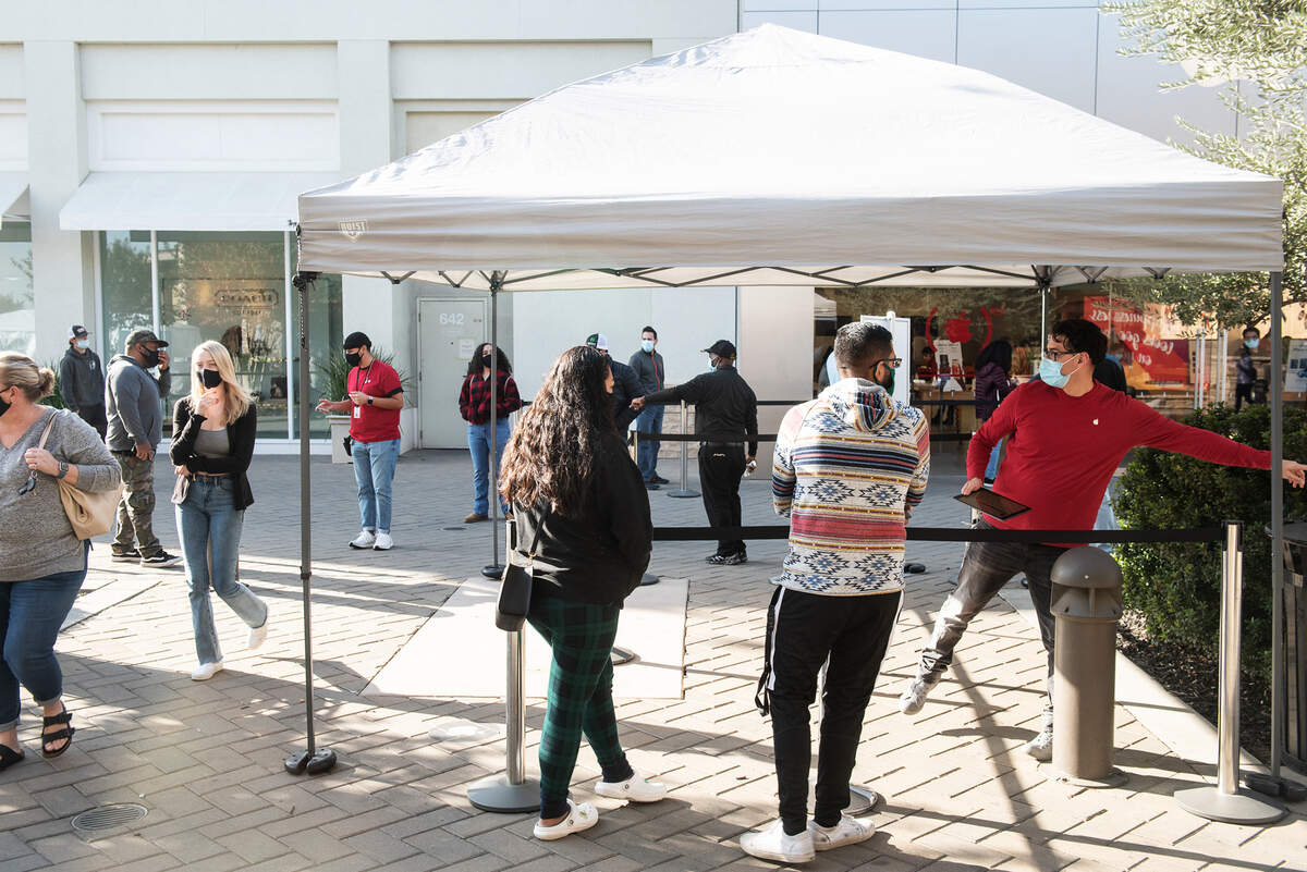 Customers wait outside the Apple Store at Vintage Faire Mall in Modesto, Calif., on Thursday, Dec. 3, 2020.