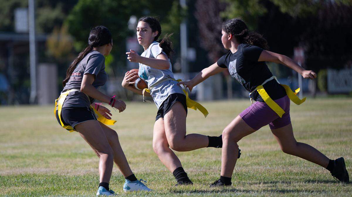 Andrea Fuentes, middle, runs the ball during Escalon girls flag football practice at Escalon High School in Escalon, Calif., Thursday, August 3, 2023.