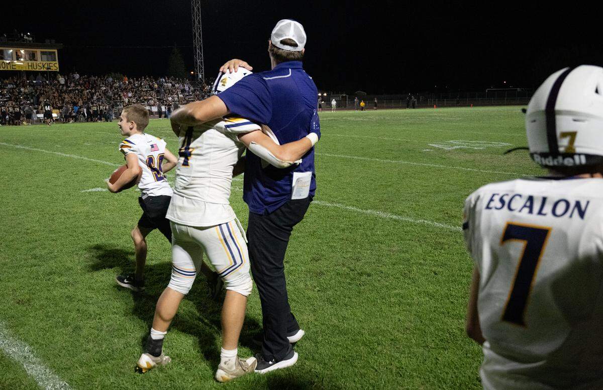 Escalon coach Andrew Beam hugs Dylan Ball after Ball returned a kick for a touchdown during the Trans Valley League game in Hughson, Calif., Friday, Oct. 4, 2024.