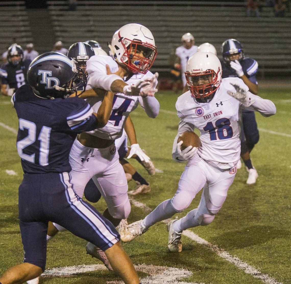 Tealen Gaines, 18, of East Union tries to get around Downey Highs, Christian Diaz, 21, with the help of Nicco Cedolini, 14, of East Union.  Downey High took on East Union Friday Aug. 17, 2018.