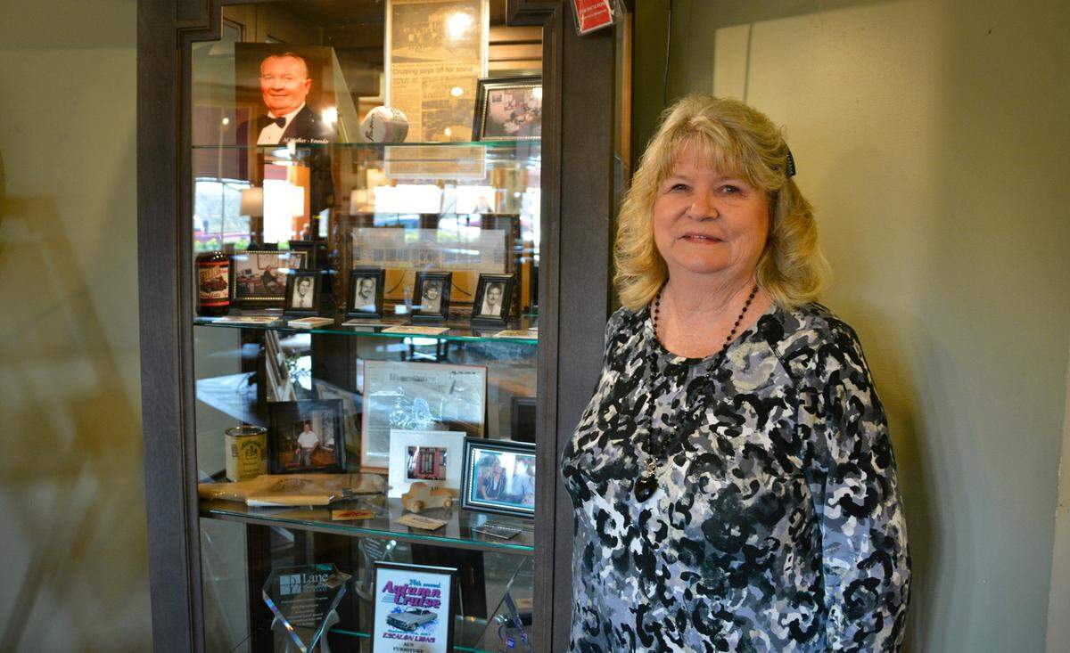 Al’s Furniture owner Kerry Walker next to a cabinet filled with memorabilia from the McHenry Avenue furniture store’s 55-year-history, including a photo of founder Al Walker (top left).