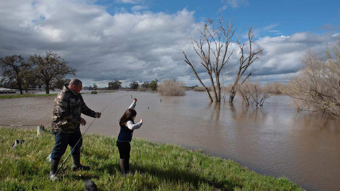 Tim Williamson and his daughter Violet, 6, do some fishing in the flooded parking lot at the San Joaquin Fishing Access on the San Joaquin River in Patterson, Calif., Wednesday, March 22, 2023.